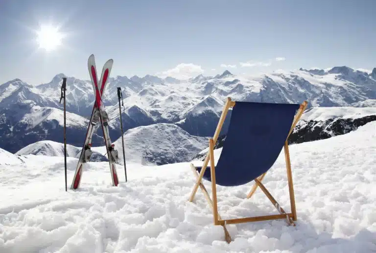 Winterurlaub in Österreich: Klappstuhl und Skier im Schnee mit Ausblick auf die verschneiten Berge
